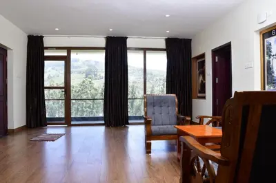 a living room with a table and chairs and large windows at LaFiesta in Kodaikānāl