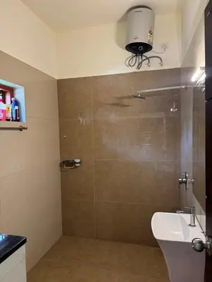 a bathroom with a shower with a toilet and a sink at Calm Serenity Homestay in Kozhikode