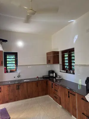 a large kitchen with wooden cabinets and counters at Calm Serenity Homestay in Kozhikode