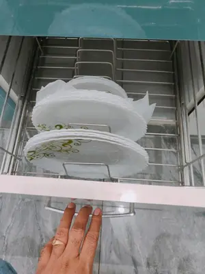 a hand is reaching for a plate in a drawer at Vani Vilas Luxury Villa in Mysore