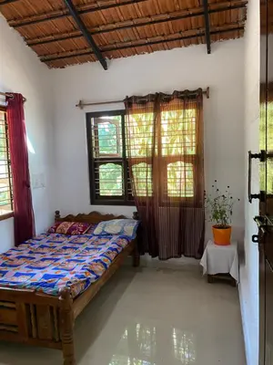 a bedroom with a bed and two windows at Nirvana Private Villa in Kushālnagar