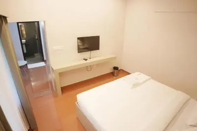 a white room with a bed and a television at Hotel Spacio in Kozhikode