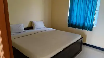 a bed in a small room with a blue window at GM nest in Coimbatore