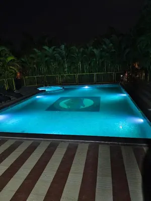 a swimming pool lit up at night at Plumeria Resort Coorg in Kushālnagar