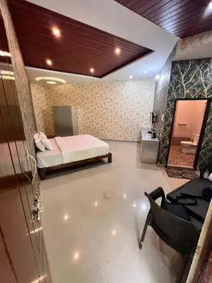 a bedroom with a bed and a chair and a bathroom at Plumeria Resort Coorg in Kushālnagar