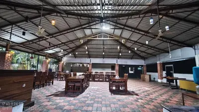 a dining room with tables and chairs in a building at Plumeria Resort Coorg in Kushālnagar