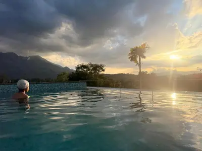 a person in a swimming pool with a palm tree at Idam home stay in Wayanad