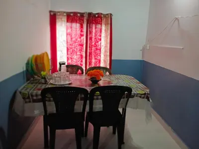 a dining room table with chairs and a red window at Varshini home stay in Kotagiri