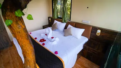 a bed with white sheets and pillows next to a tree at Era Resort Slope Stay in Kodaikānāl