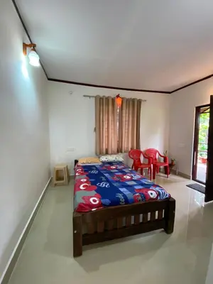 a bedroom with a bed and a table and chairs at Coorg jungle Cottage in Kushālnagar
