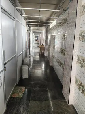 a hallway with a long corridor with tiles on the walls at Hotel Nirmal Cottage Gobichettipalayam in Siruvalūr