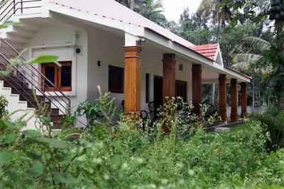 a small white house with columns and a staircase at Nirmala Dhama Farmstay - Serene Family Retreat