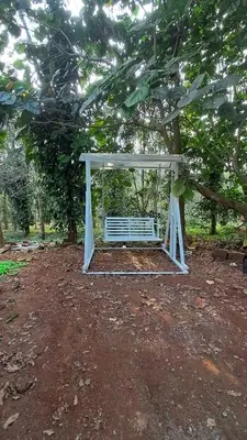 a white bench sitting under a tree at Aura Eco Friendly Resort in Sultan Bathery