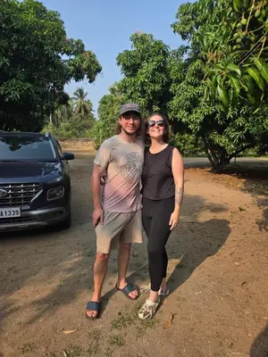 a man and a woman standing next to a car at Mango Bite Farmstay in Pollāchi