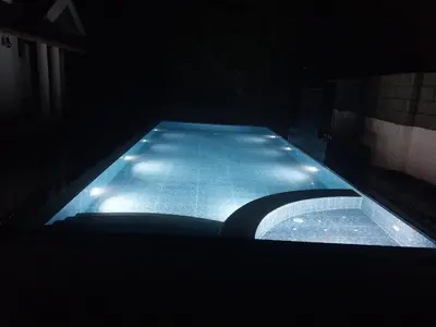 a swimming pool at night with lights on it at Salisbury Manor Heritage Inn in Marayoor
