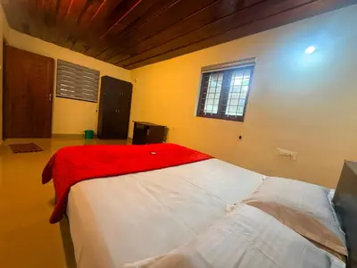 a bedroom with a bed with a red blanket on it at Wayanad Shas Villa in Padinjarathara