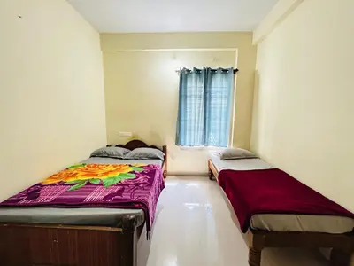 two beds in a room with a window at Raya 2 bhk flats in Mysore