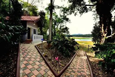a house with a brick walkway next to a river at Finca Backwater Homestay in Suntikoppa
