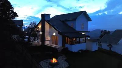 a small white house with a fire in front of it at 3 Bhk Villa Ooty - Casa de Amor by EBR in Ooty