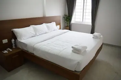 a bedroom with a large bed with white sheets and towels at KK Service Suites in Coimbatore