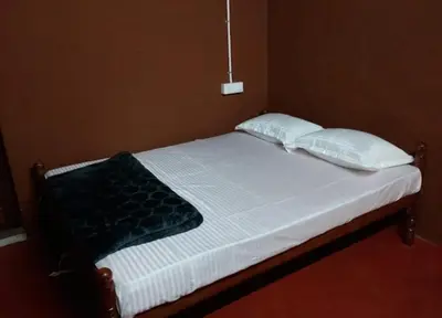 a bed with two pillows and a blanket on it at Magizh Kudil The Mud House in Marayoor