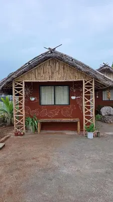 a house with a roof with a bench in front of it at Magizh Kudil The Mud House in Marayoor