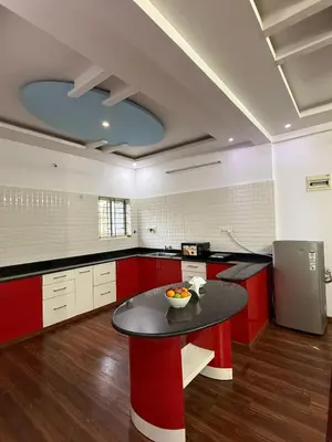 a large kitchen with red cabinets and a table at Siddhartha Residency in Mysore