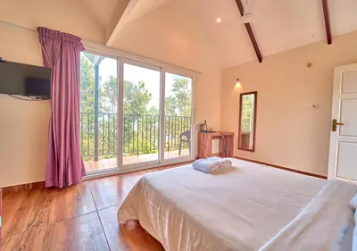 a bedroom with a large bed and a large window at Gardenia Pool Resort Kanthalloor by VOYE HOMES Mountain View Stay Near Bhramaram view Point in Kanthalloor