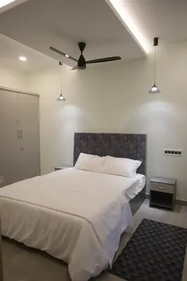 a bedroom with a large white bed with a ceiling fan at Castle DAK in Trichūr