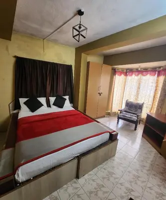 a bedroom with a large bed and a chair at DADIL HOME STAY ooty in Ooty