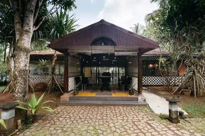 a pavilion with a table in front of a house at Discovery Village Kabini in Antarasante