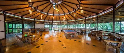 a large room with tables and chairs and windows at Discovery Village Kabini in Antarasante