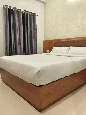 a bedroom with a wooden bed with a black curtain at Hotel Riviera in Mananthavady