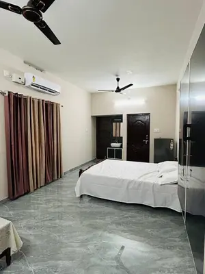 a bedroom with a large bed and a ceiling fan at Cosy Stays, 2 Adjacent Apartments in Irinjalakuda in Irinjālakuda
