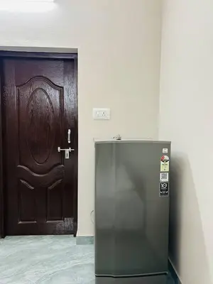 a large wooden door with a refrigerator in front of it at Cosy Stays, 2 Adjacent Apartments in Irinjalakuda in Irinjālakuda