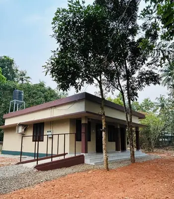 a small building with two trees in front of it at Cosy Stays, 2 Adjacent Apartments in Irinjalakuda in Irinjālakuda