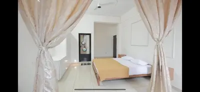 a white bedroom with a bed and curtains at AZURE stay happy in Pudunagaram