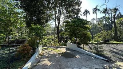 a garden with a fence and trees in the background at Hima Pool Villa in Padinjarathara