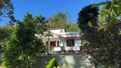 a white house with trees in front of it at Hima Pool Villa in Padinjarathara