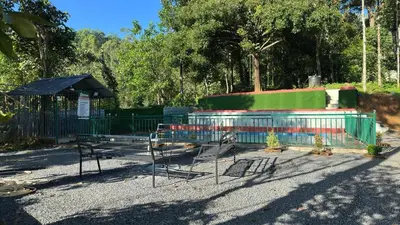 a park with a fence and chairs and an umbrella at Hima Pool Villa in Padinjarathara