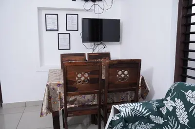 an old wooden chair with a tv on a wall at Serene Cottage - Home away from Home in Vythiri