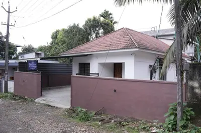 a white house with a fence in front of it at Serene Cottage - Home away from Home in Vythiri