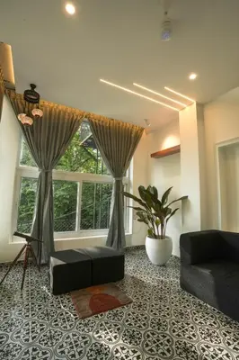 a living room with a couch and a window at SUKOON Stays - Nestled among the misty hills and lush forests in Vythiri