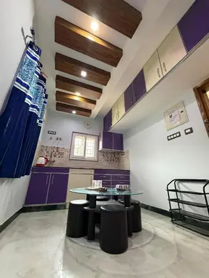 a kitchen with purple cabinets and a table and stools at Forever Cottage by sait's hospitality in Ooty