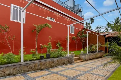 a red house with plants in the courtyard at Palette Mithalai Farm by CheckIn | Garden | Pvt Pool | Coimbatore in Coimbatore