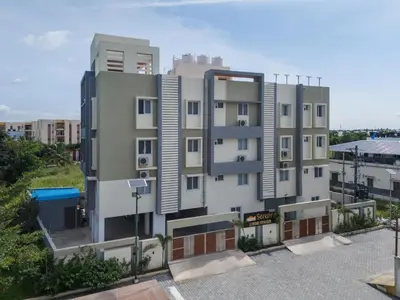 a tall white building in a parking lot at Everest Serenity Service Apartment in Pīlamedu