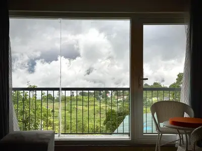 a room with a large window with a view of a field at Black Dot Stays - Mehand Veera Residency in Kodaikānāl