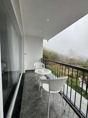 a balcony with a table and chairs and a view at Black Dot Stays - Mehand Veera Residency in Kodaikānāl