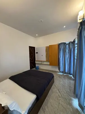 a bedroom with a large bed with blue curtains at Black Dot Stays - Mehand Veera Residency in Kodaikānāl