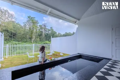 a little girl sitting on a bench next to a swimming pool at StayVista at Mudra Tattva - Pvt Pool,Lawn,Jacuzzi 2BR Luxury Rooms in Suntikoppa